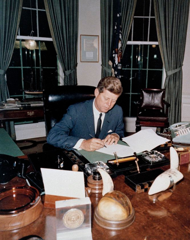 President Kennedy signs the Cuba quarantine proclamation at his Oval Office desk.