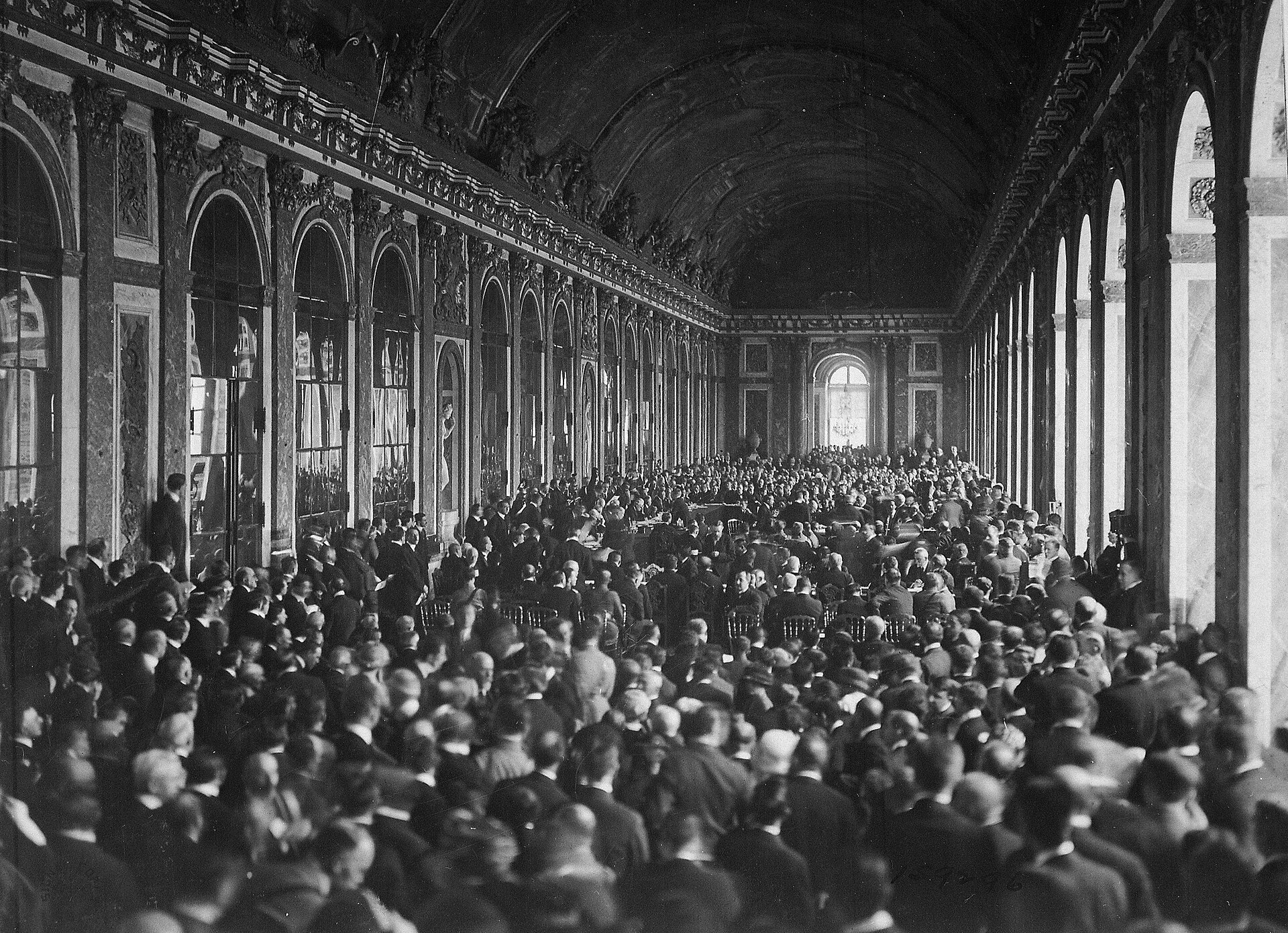 Delegates fill the Hall of Mirrors at Versailles around a central signing table.