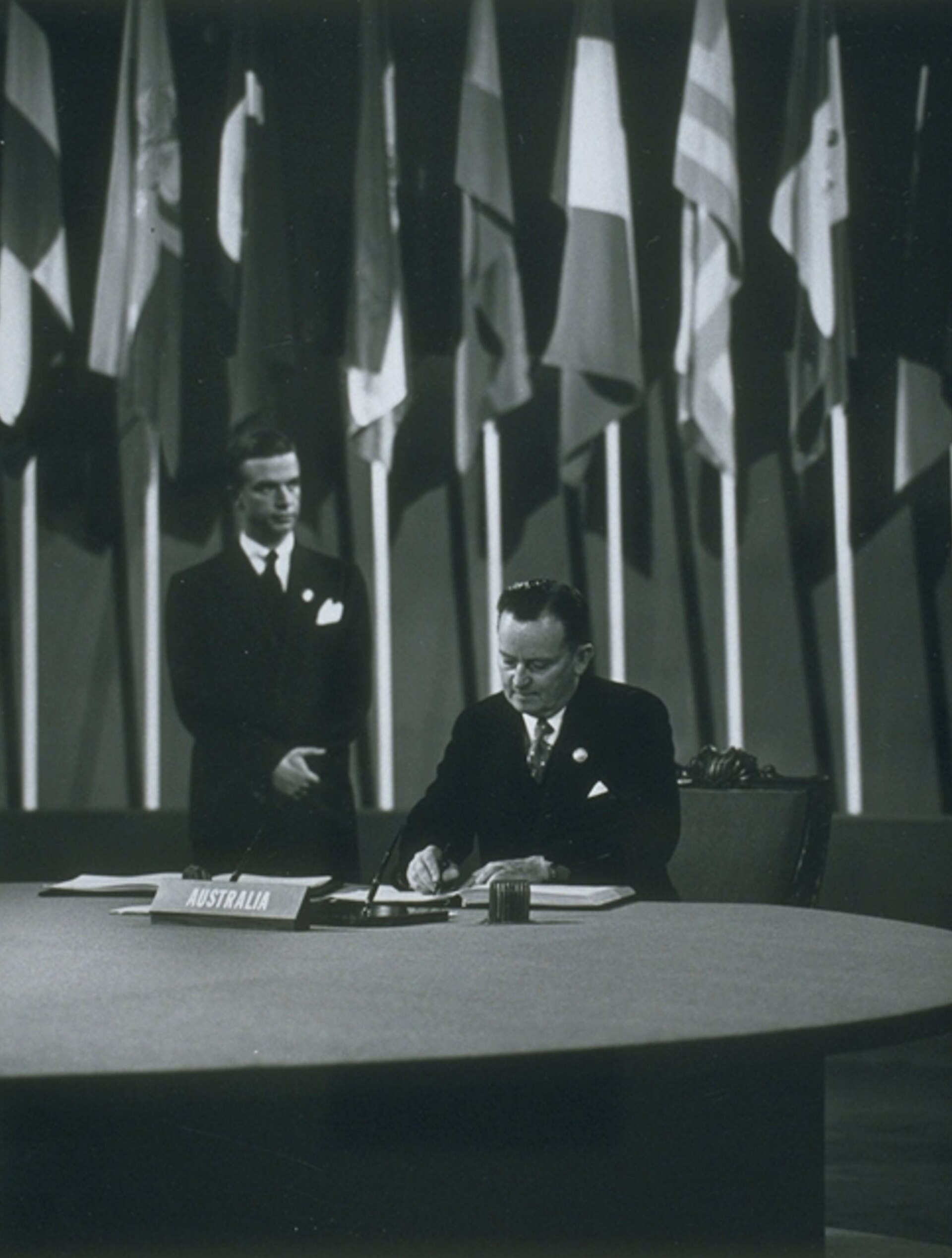 Australian deputy prime minister Frank Forde signs the United Nations Charter while delegates watch.
