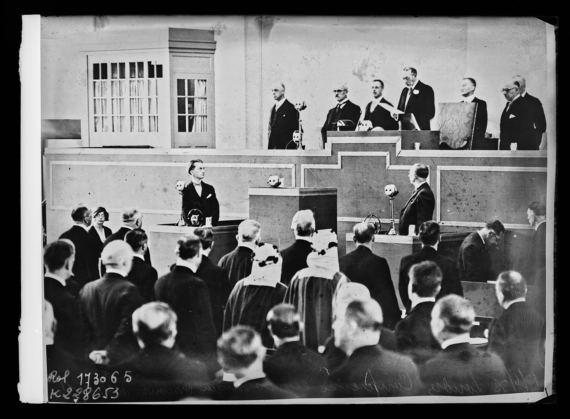 King George V delivers a speech from a platform to delegates assembled for the London Economic Conference.