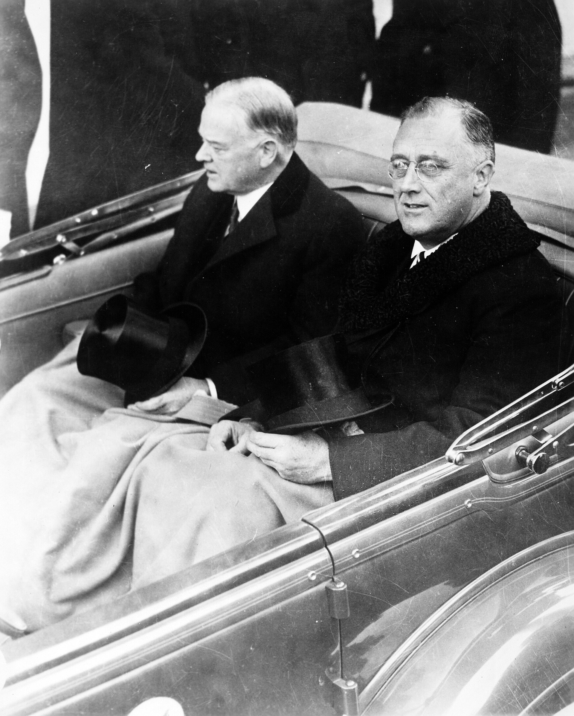 Franklin Roosevelt and Herbert Hoover sit together in an open car on the way to the United States Capitol.