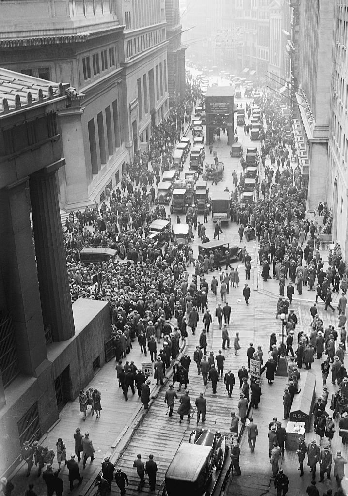 A dense crowd gathers outside the New York Stock Exchange beneath the building's columns on Black Tuesday.