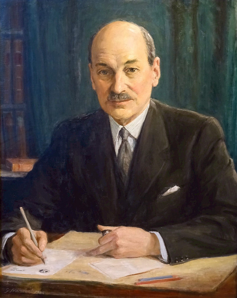 British prime minister Clement Attlee sits in a dark suit against a brown background.