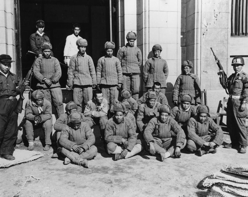 Captured Chinese soldiers stand under guard after entering the Korean War alongside North Korean forces.