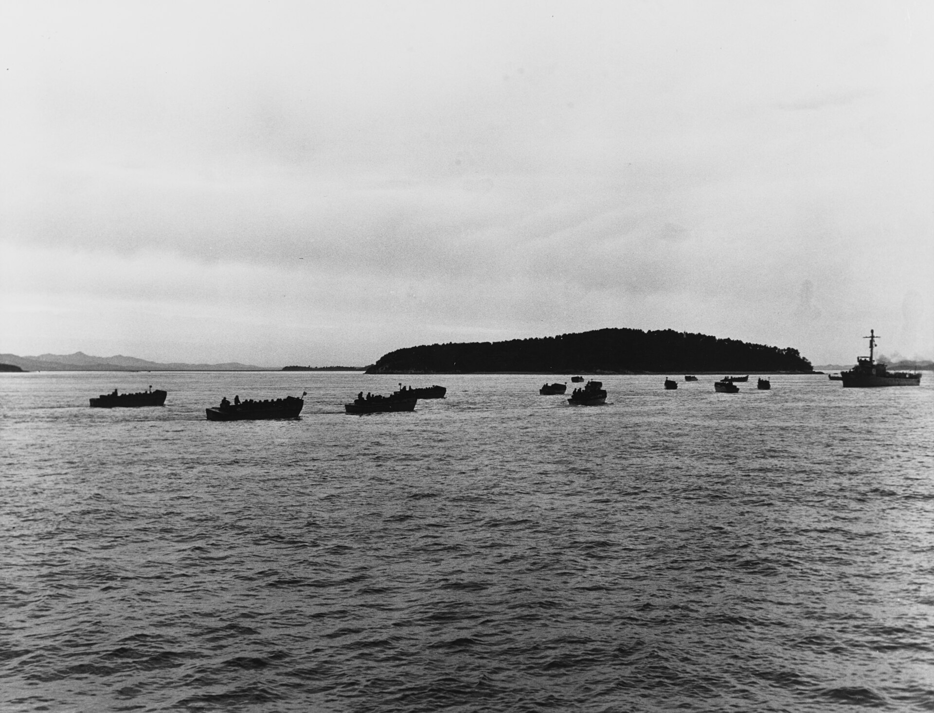 Landing craft carrying the first assault wave cross the water toward the seawalls at Inchon.