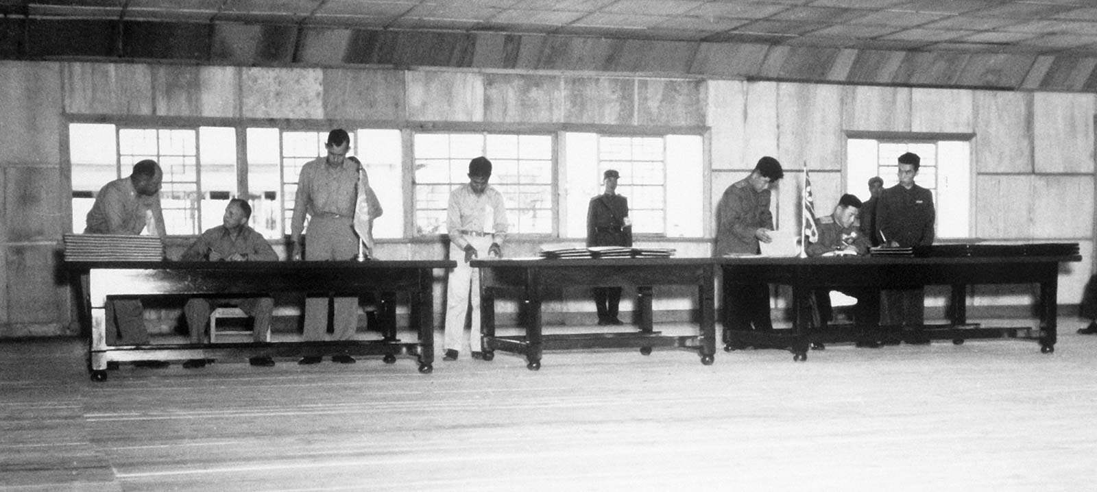 Lieutenant General William Harrison and General Nam Il sign the Korean Armistice Agreement at separate tables.