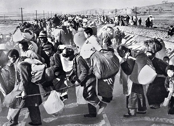 South Korean civilians carrying bundles move along a road after fleeing the North Korean invasion.