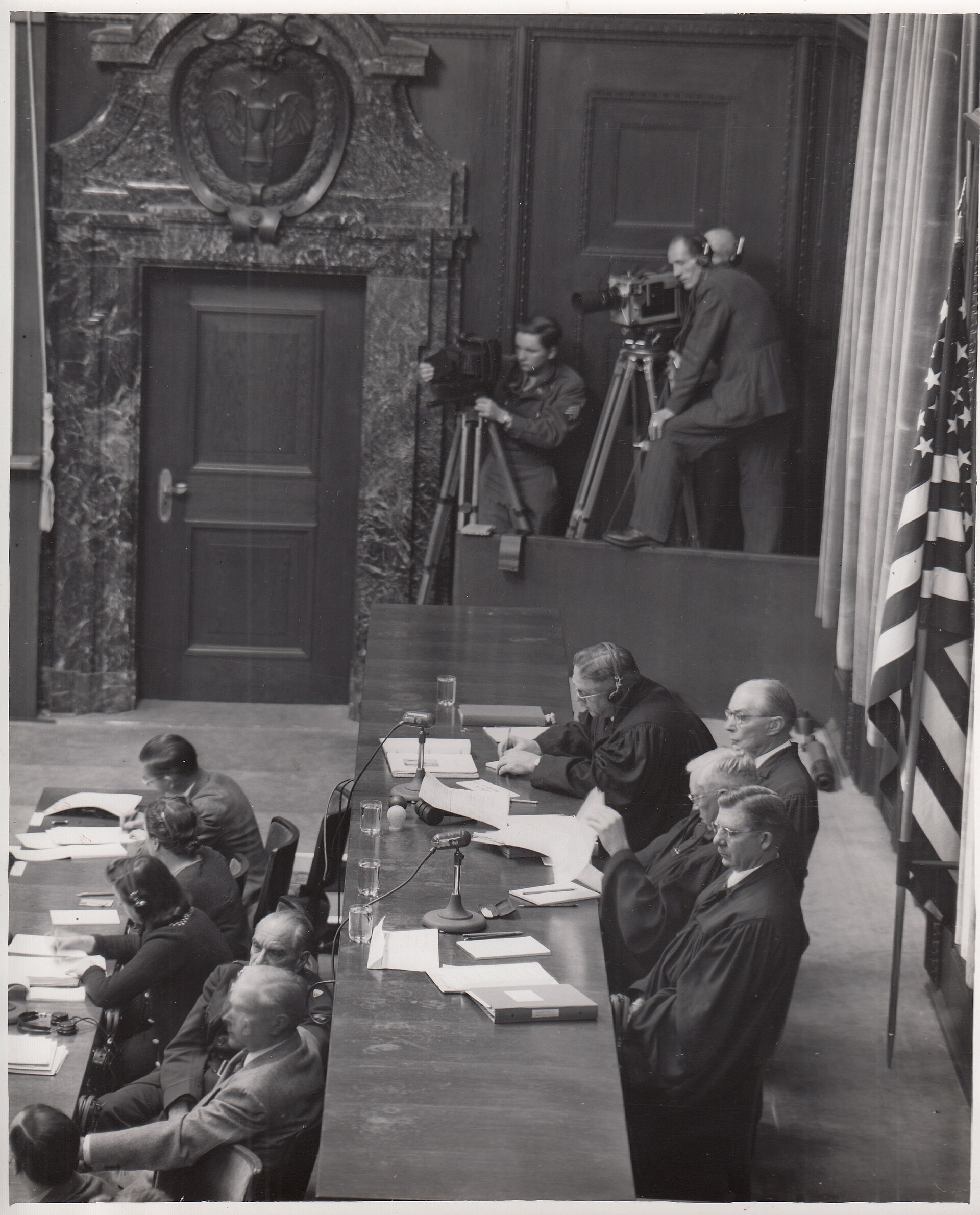 Three American judges in robes sit behind the bench of a United States military tribunal at Nuremberg.