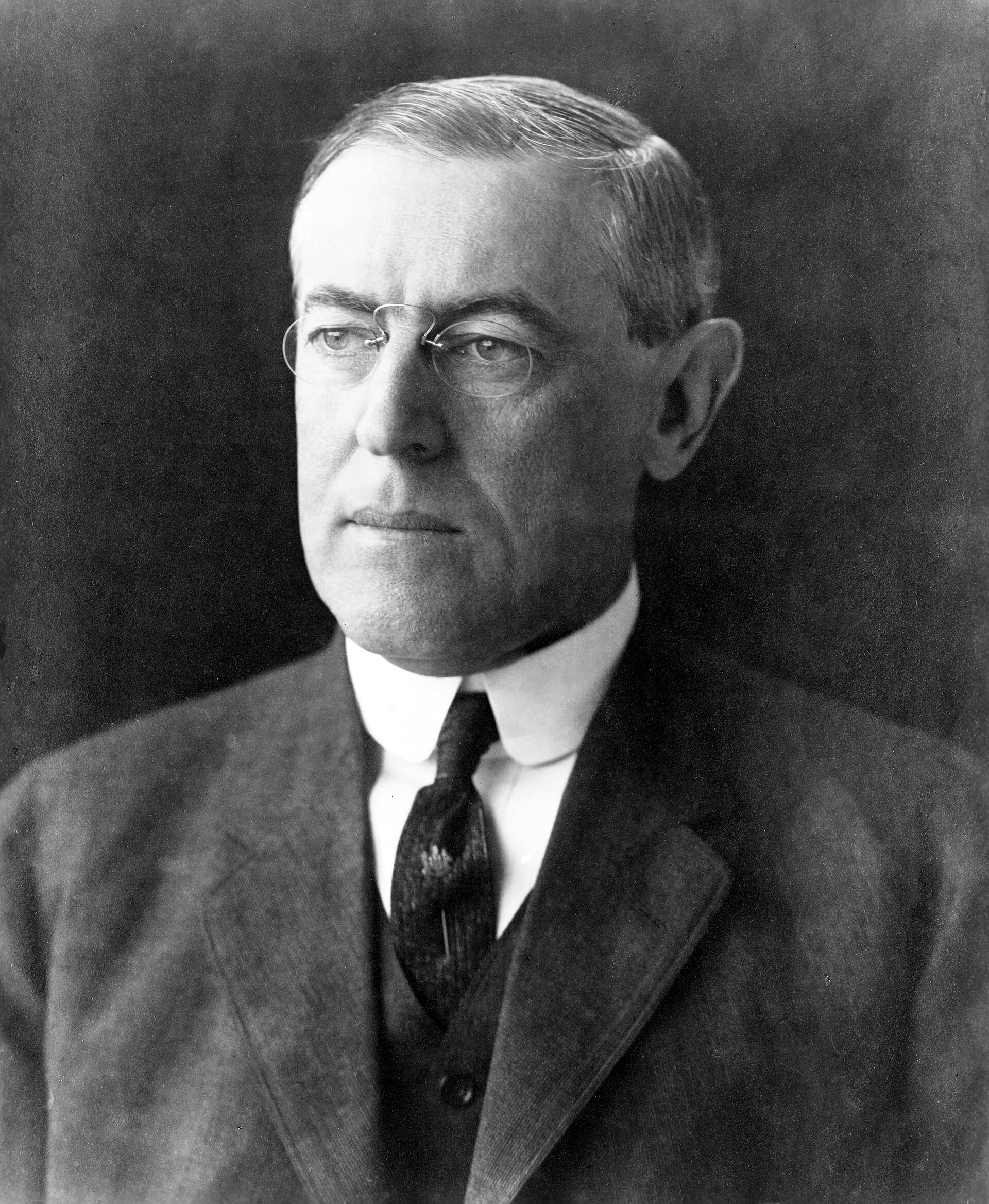 A formal portrait photograph of Woodrow Wilson in a dark suit and pince-nez.