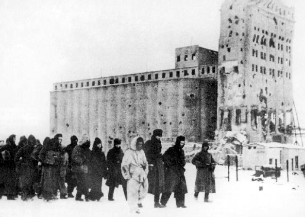 A long column of exhausted German prisoners crosses a snowy landscape after Stalingrad.
