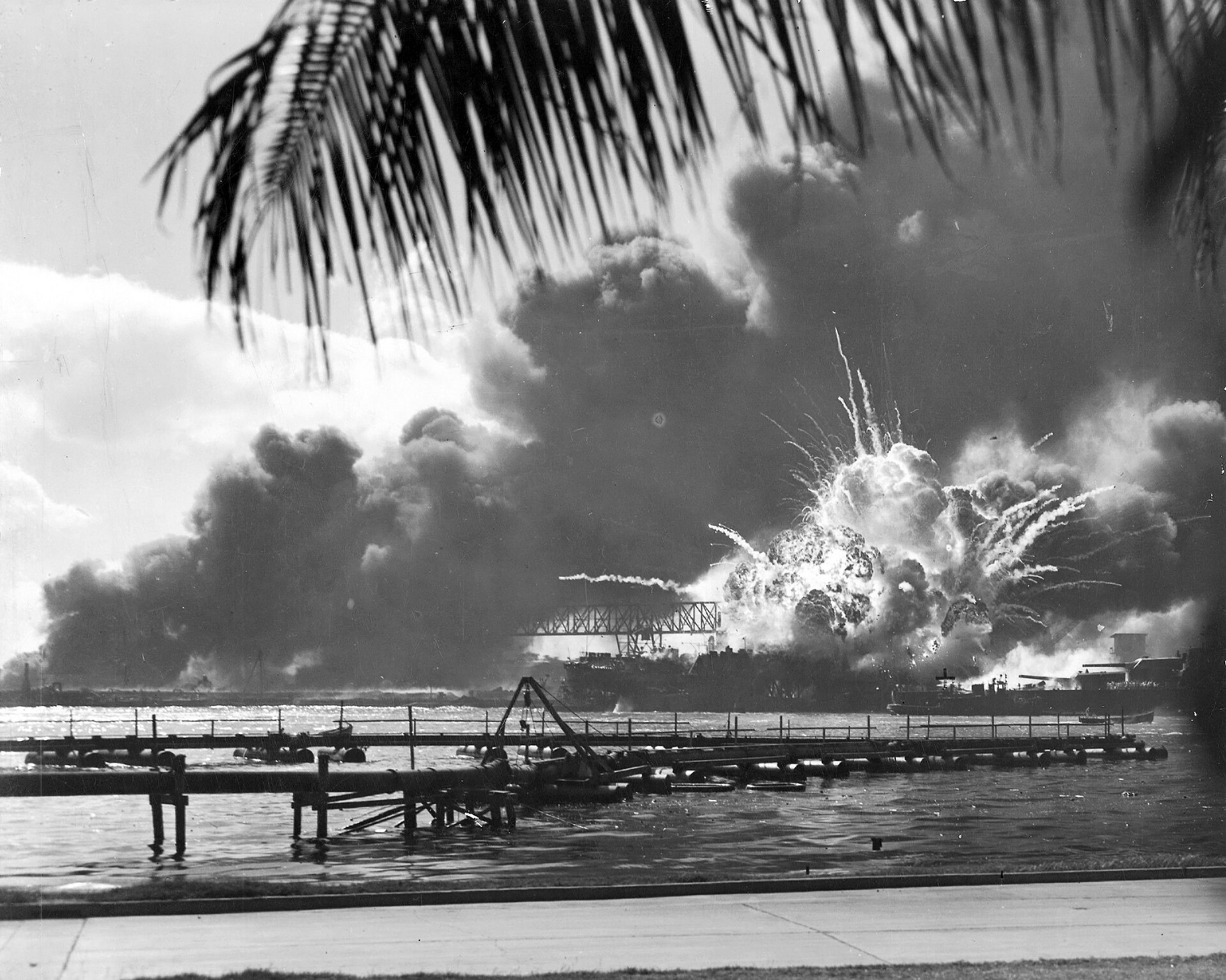 A towering explosion erupts from USS Shaw above the smoke-covered harbor.
