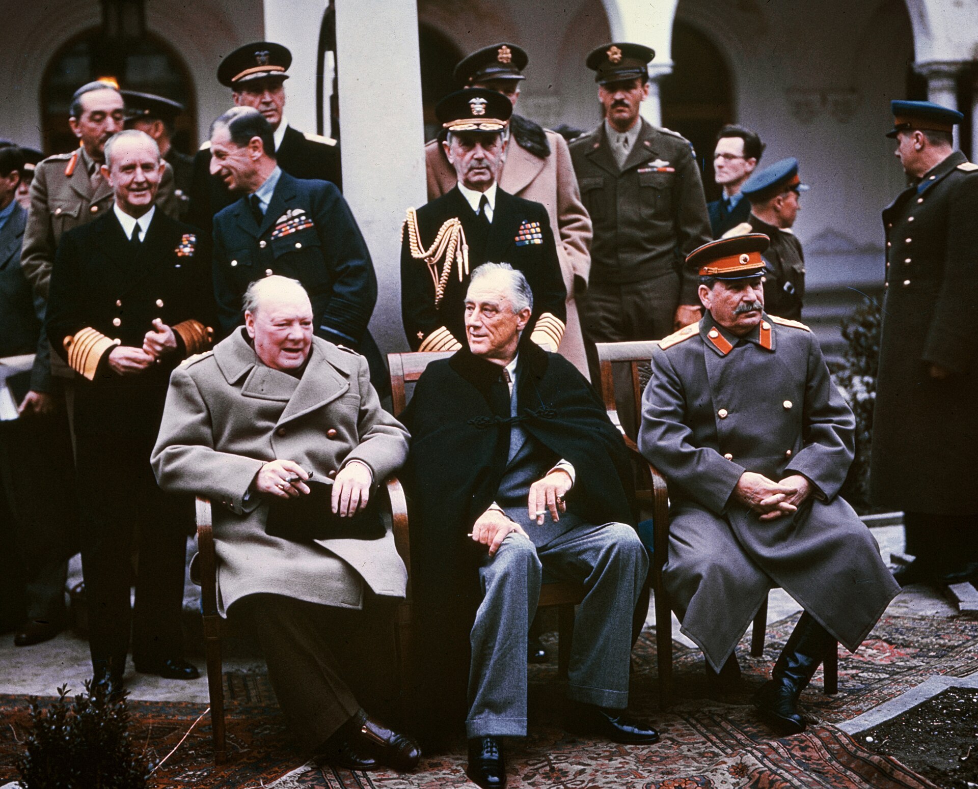 Winston Churchill, Franklin Roosevelt, and Joseph Stalin sit together among officials at Yalta.