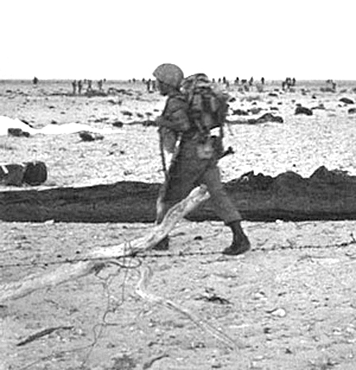 An Israeli paratrooper stands in the rocky Sinai landscape after landing near Mitla Pass.