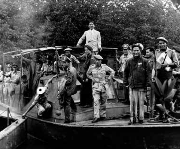 South Vietnamese president Ngô Đình Diệm smiles while standing aboard a naval vessel with military personnel.