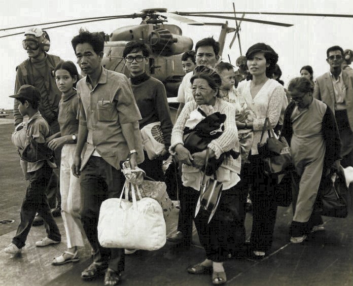 South Vietnamese refugees walk in a line across the crowded deck of a United States Navy ship during the evacuation of Saigon.